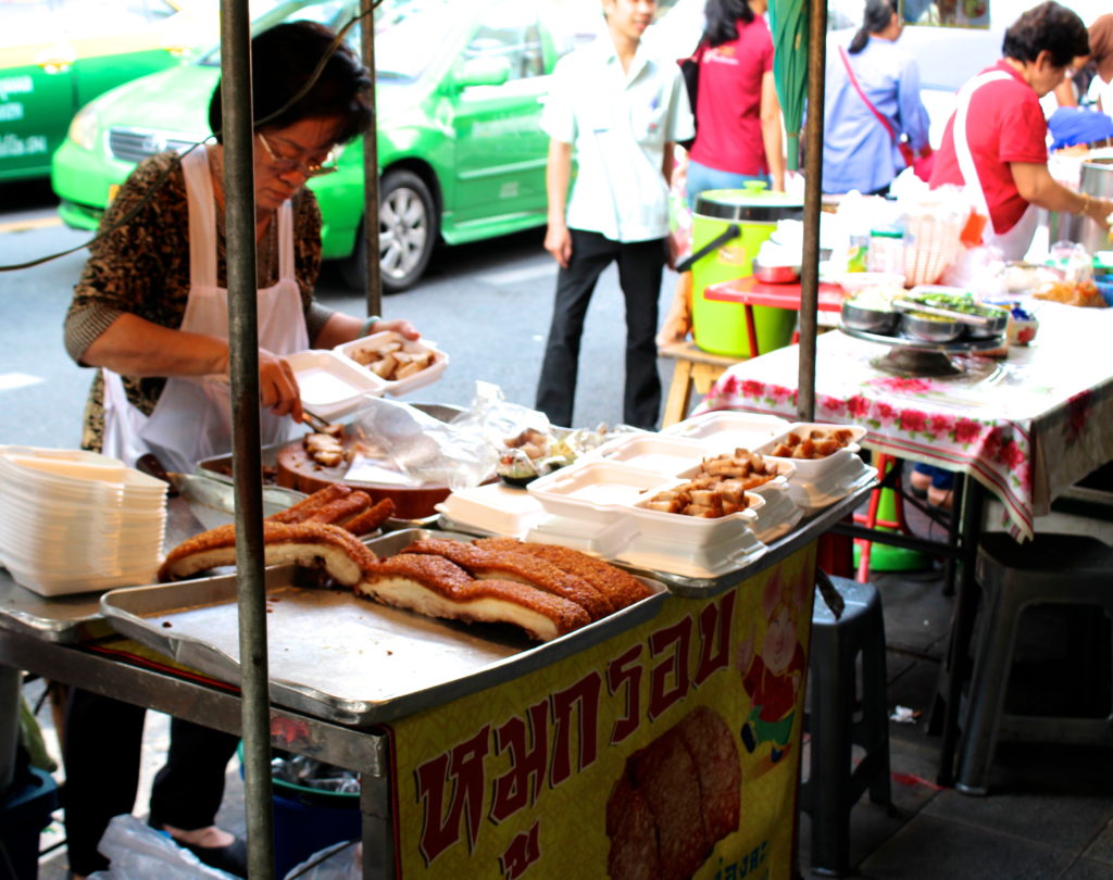 A vendor prepares crispy pork belly for hungry market-goers.